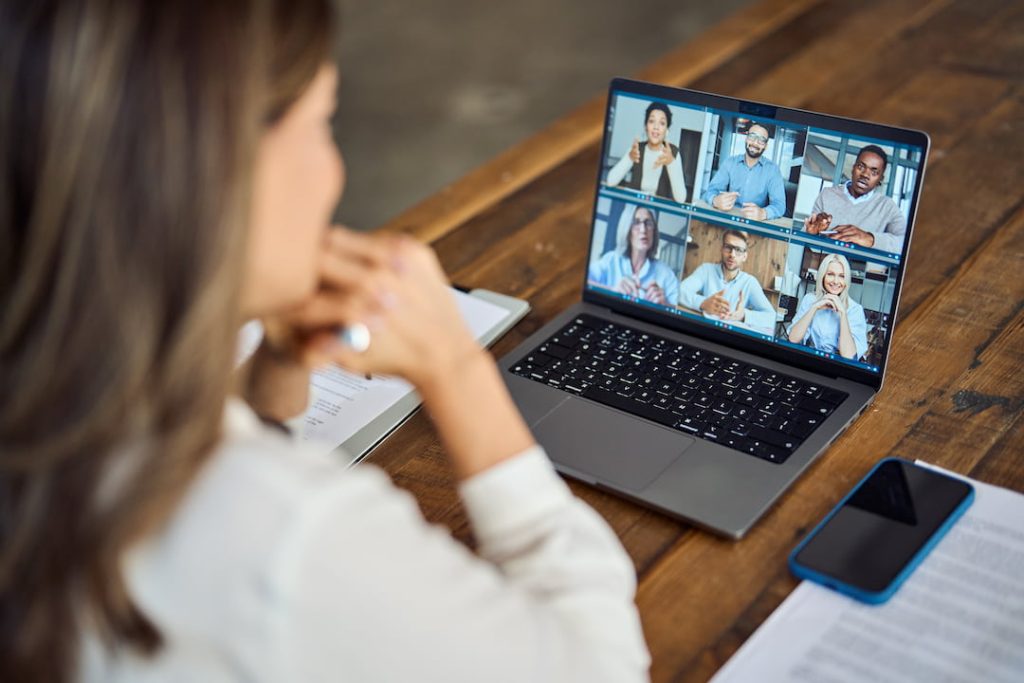 Woman attending a virtual sales kickoff on her laptop with a group of coworkers on a Zoom call.